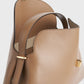 A close-up of Toteme's T-Lock Top Handle Bag in tan Palmellato leather with gold hardware, featuring one handle, an open top, and a beige interior lining.