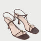 The Loeffler Randall Triana Mid Heel Sandal features brown nappa leather, strappy design, square toes, and gold round accents on the front straps, shown against a white background.