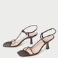 The Loeffler Randall Triana Mid Heel Sandal features brown nappa leather, square toes, thin straps with ankle buckles, and a gold ornament on each front strap, shown against a white background.