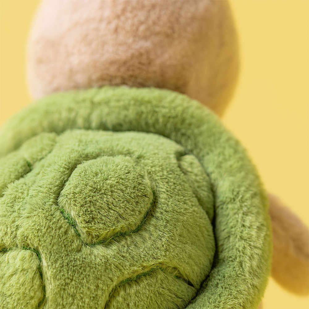 Close-up of Jellycat's Thimble Turtle, the ideal adventure companion, highlighting its soft green shell and brown body against a cheerful yellow background.