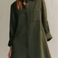 A person wearing TWP's Jenny's Coated Linen Gown, a long-sleeve olive green shirtdress featuring a front pocket and a point collar.