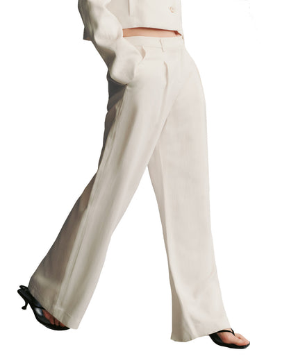 Person walking in satiny smooth, white TWP Sullivan Pant and black heels.