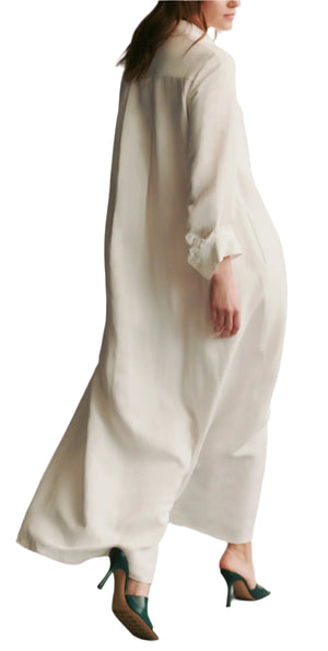 A woman in the TWP Jennys Coated Linen Gown, an oversized white shirt dress with an A-line silhouette, walks away in dark green high heels, seen from the back.