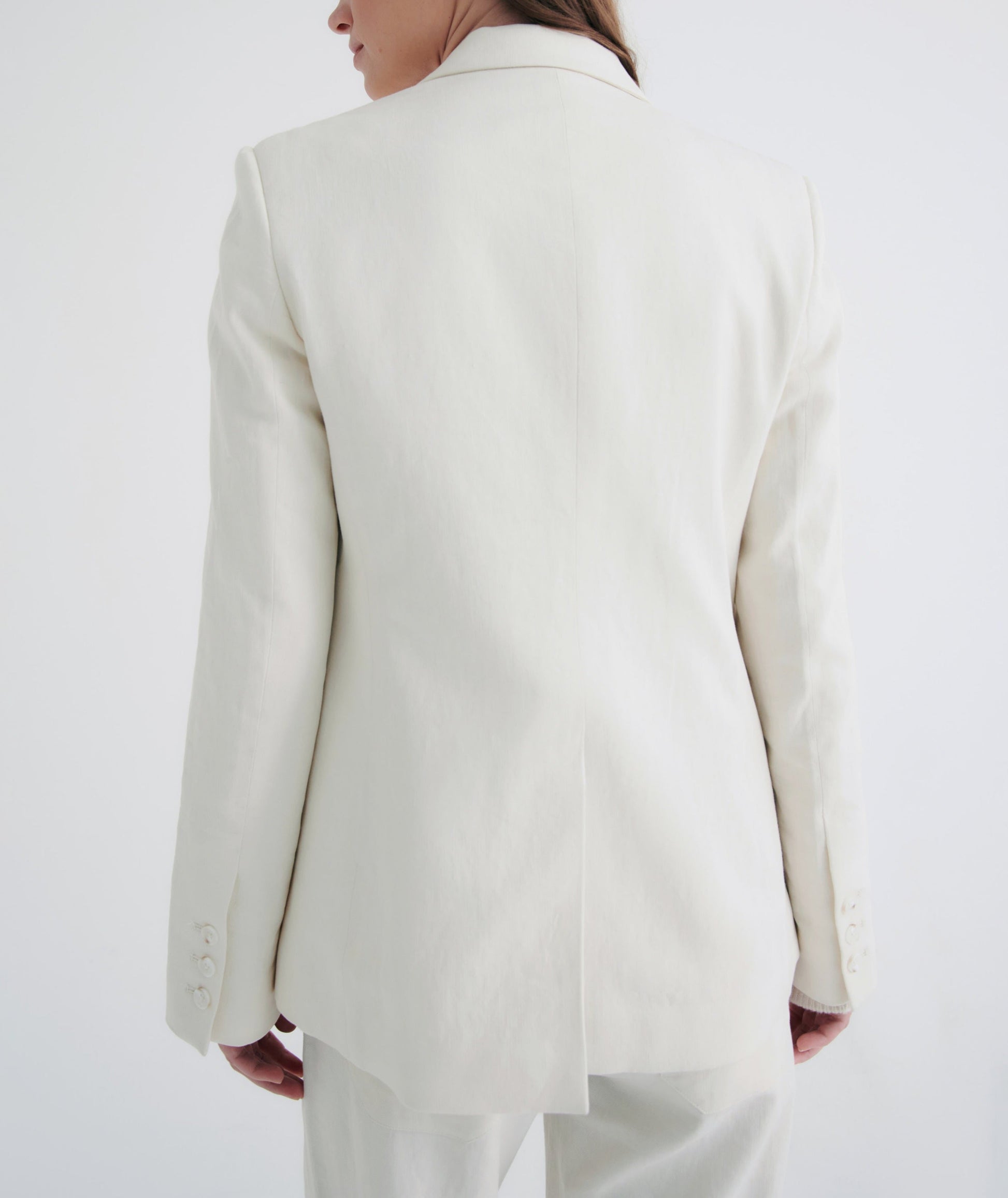 Rear view of a person wearing a stylish TWP Husband Linen Jacket with notched lapels and a split tail design, against a plain background.