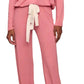 A woman wearing the Eberjey EBJ Gisele Slouchy Set—loose-fitting, long-sleeve pink pajamas made from sustainable TENCEL™ Modal, featuring a white waist tie and gathered ankle cuffs—stands barefoot in ultimate comfort.