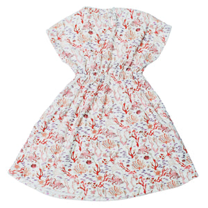 The Delphine Dress by Timo & Violet is a white organic cotton summer dress for girls, with short sleeves, a cinched waist, and a colorful Rosy Coral Reef print of coral, fish, and seashells.