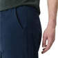 A close-up of a person wearing Rag & Bone’s Tapered Nylon-Blend Trouser in dark blue, paired with a dark green shirt, their right hand relaxed by their side.