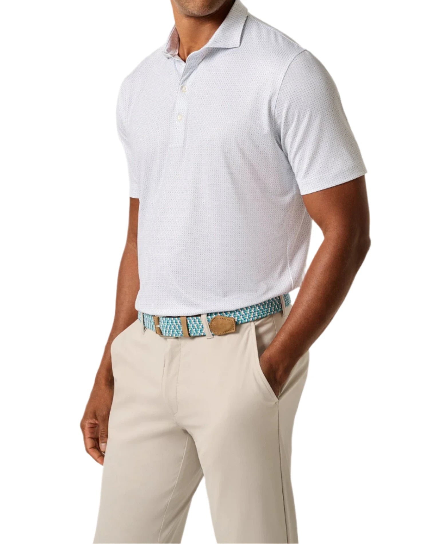 A man wearing a Johnnie-O Tee Time Polo, featuring moisture-wicking lightweight fabric, and beige pants with a blue patterned belt stands against a white background.