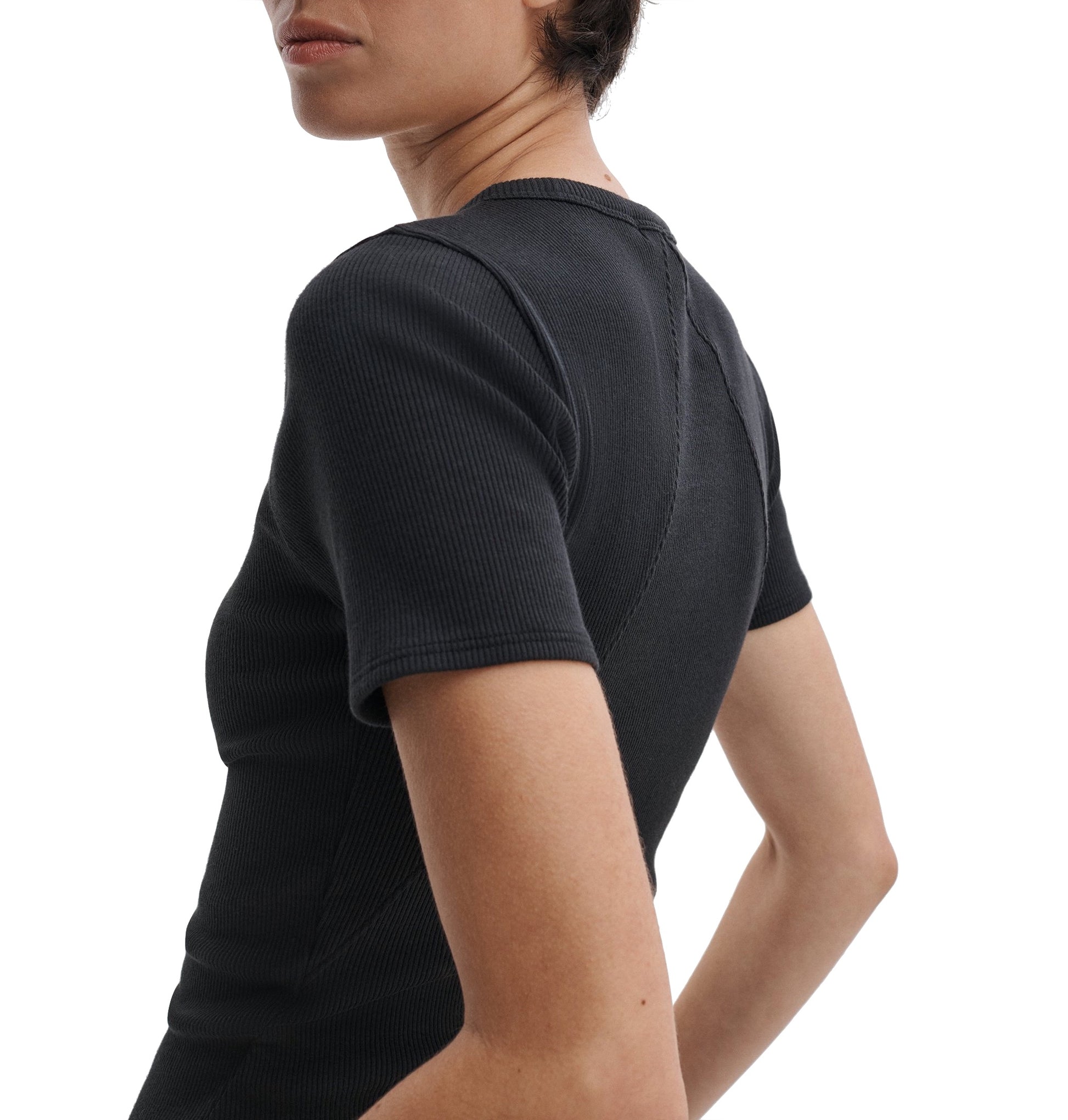 A person is shown from the side and back, wearing Rag & Bone's Essential Ribbed Tee—a fitted, black short-sleeve top made from organic cotton—making it a modern wardrobe staple.