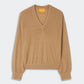 The Airy V by Guest in Residence—a tan lightweight cashmere V-neck sweater featuring long sleeves, ribbed cuffs and hem, and subtle contrast trim—perfect for effortless summer layering; shown laid flat against a plain light background.