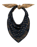 A navy blue and tan reversible paisley jacquard The Wild Rag by Guest in Residence, tied in a knot at the top with the pointed end hanging down.