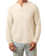 A man wearing a cream Faherty Long-Sleeved Cloud Henley and light blue jeans, standing against a white background.
