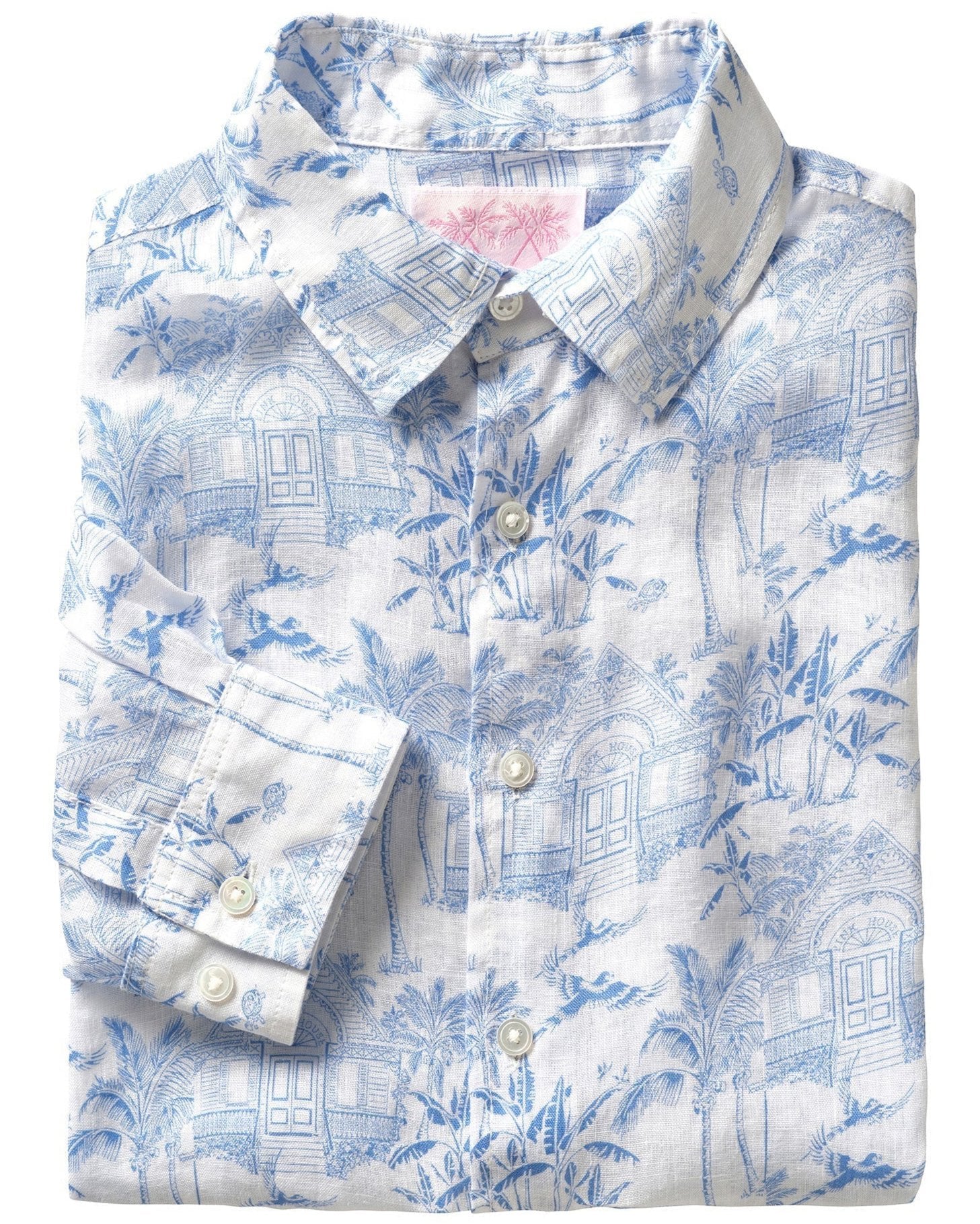 The Pink House Mustique Printed Linen Shirt by Pink House Mustique offers a pre-washed, folded white button-up shirt adorned with a blue tropical print featuring palm trees and houses, creating a relaxed yet stylish vibe.