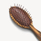 The Machete Petite Travel Detangling Hair Brush, featuring a brown, oval shape crafted from elegant Italian acetate and equipped with plastic detangling bristles and rounded tips, is displayed against a plain white background.