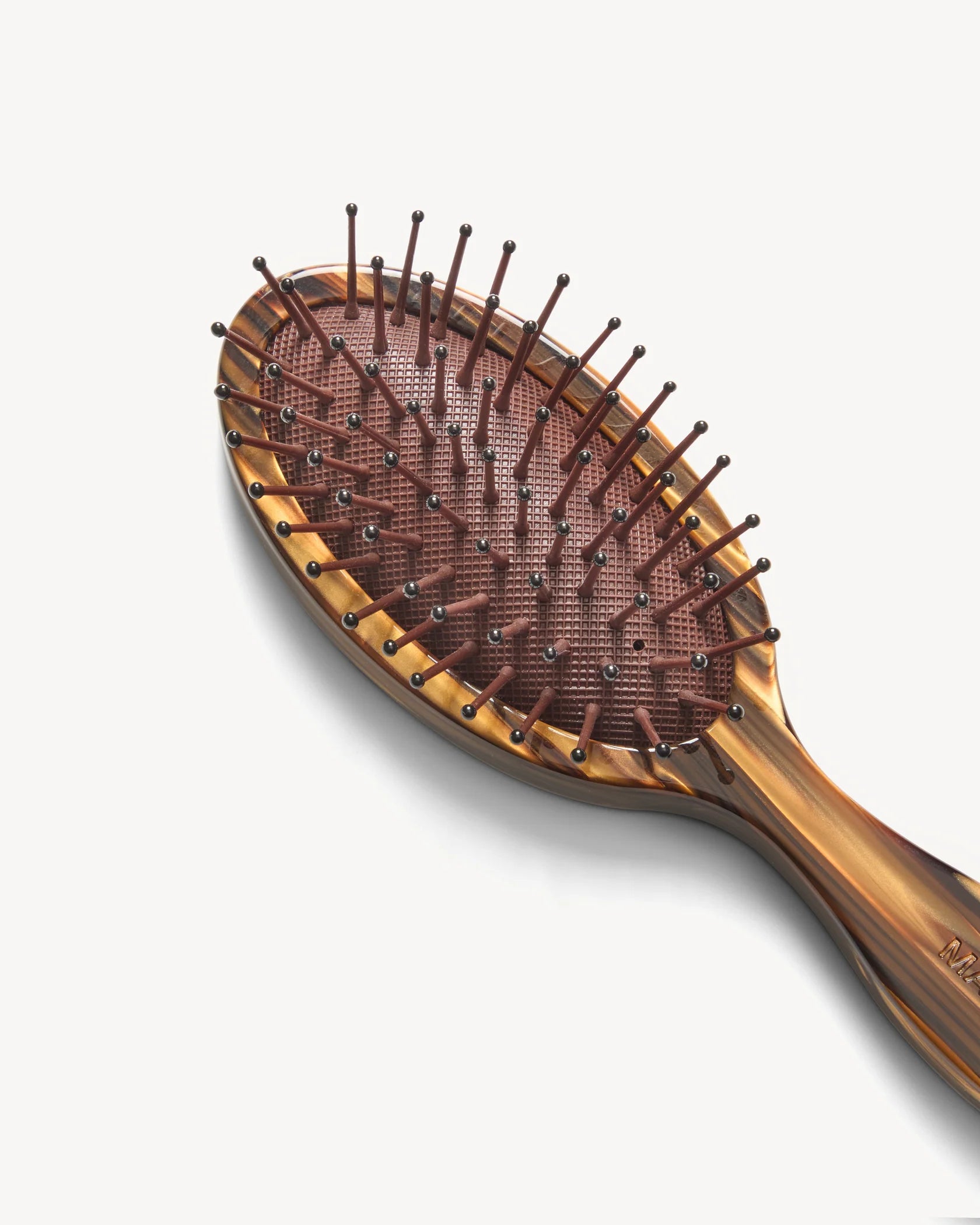 The Machete Petite Travel Detangling Hair Brush, featuring a brown, oval shape crafted from elegant Italian acetate and equipped with plastic detangling bristles and rounded tips, is displayed against a plain white background.