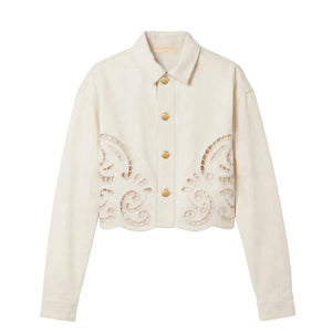 A cream-colored, long-sleeve button-up jacket from Ulla Johnson, The Bobbi Eyelet Jacket, featuring gold buttons and intricate eyelet embroidery cut-out patterns along the lower front and hem.