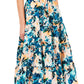 A woman complements her look with the Ulla Johnson Ottilie Dress, a printed cotton piece featuring a belted waist and short sleeves, perfectly paired with floral-patterned heeled sandals.