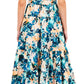 Standing against a white backdrop, a person models the Ottilie Dress by Ulla Johnson, featuring floral patterns in blue, green, and peach brushstrokes.