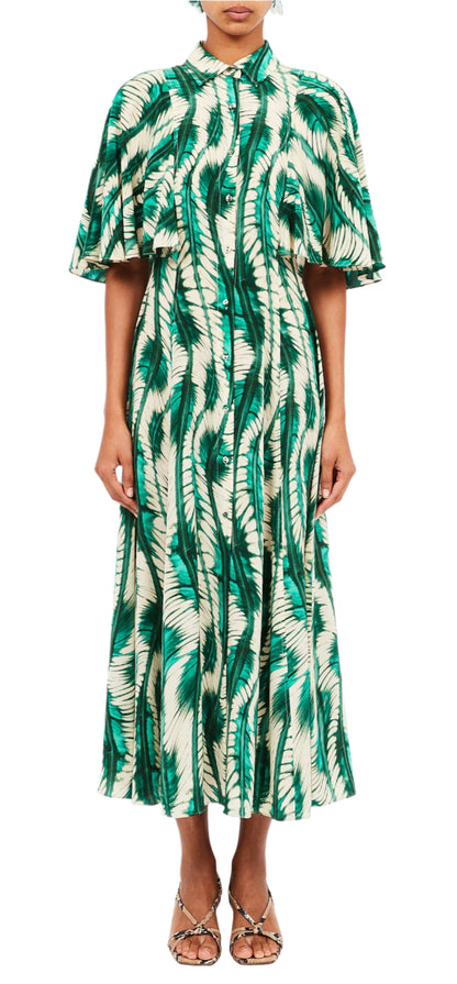 Someone is dressed in a luxurious Silhuette Dress by Ulla Johnson, featuring a green and white pattern, made from 100% silk with a cape-like top and button-down front.