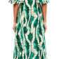 Back view of a person wearing Ulla Johnson's Silhuette Dress, a long green and white patterned piece made from 100% silk, with short sleeves and open heels.