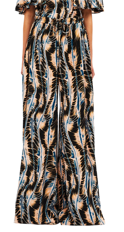 Someone wearing Ulla Johnson's Sawyer Pant, styled in wide-leg fashion and made from 100% silk, featuring an abstract wavy pattern in black, beige, and blue.