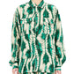 A person wearing Ulla Johnson's Soren Shirt, a green and beige patterned design with matching pants, crafted from 100% silk, stands with arms relaxed.