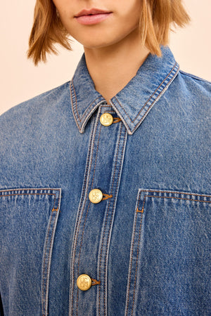 A close up of a person's shirt, featuring the blue denim Arquette Jacket by Ulla Johnson in a relaxed fit.