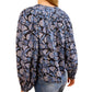 A person in the Ulla Johnson Florelle Blouse, featuring a voluminous fit with blue and black ikat-inspired florals, paired with blue jeans and viewed from the back.