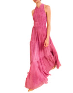 A person wearing Ulla Johnson’s Freesia Gown, a magenta, sleeveless, floor-length dress with tiered crinkle chiffon and a halter neckline.