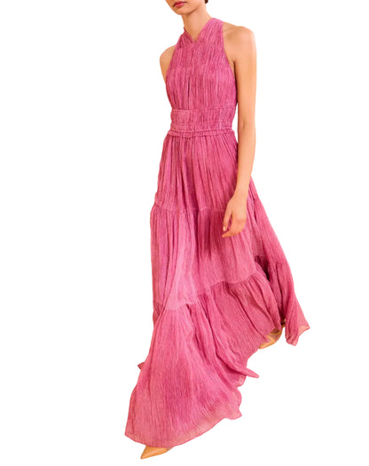 A person wearing Ulla Johnson’s Freesia Gown, a magenta, sleeveless, floor-length dress with tiered crinkle chiffon and a halter neckline.