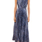 A woman in the Ulla Johnson Malin Satin Dress—a sleeveless, ankle-length blue and black patterned pleated midi—stands against a white background wearing black strappy shoes.