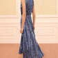 A woman wears the Ulla Johnson Malin Satin Dress—a sleeveless blue and black pleated midi—with black heeled sandals as she walks indoors on a carpeted floor with cream paneled walls.