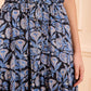 A person wears a sleeveless, ribbed tan top paired with the Ulla Johnson Nessa Skirt—a high-waisted, cotton-blend piece featuring batik-inspired florals.