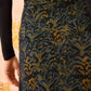 Someone stands facing away from the camera wearing a long-sleeve black tricot jersey top and the Ulla Johnson Paola Jersey Skirt, a high-waisted A-line skirt featuring a dark abstract leafy pattern.