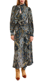 A woman wears the Ulla Johnson Sabrina Silk Dress, featuring long sleeves, a paisley print, crepe de chine fabric, and ruffle details, paired with tan boots.