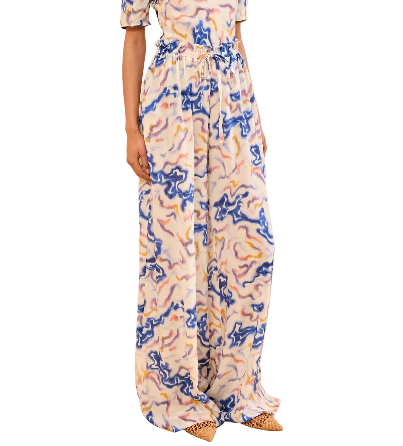 Someone wearing the Sawyer Silk Pant by Ulla Johnson in a vibrant blue, yellow, and pink abstract silk crepe de chine with wide legs and a high waist, paired with pointed-toe shoes.