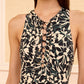 A woman wearing the Ulla Johnson Solina One Piece, a sleeveless dress featuring a black and beige abstract leaf pattern and lace-up detailing at the neckline.