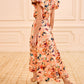 A woman in the Ulla Johnson Sophea Skirt stands on a patterned carpet in a room with cream paneled walls, pairing the botanical peach skirt with beige heels.