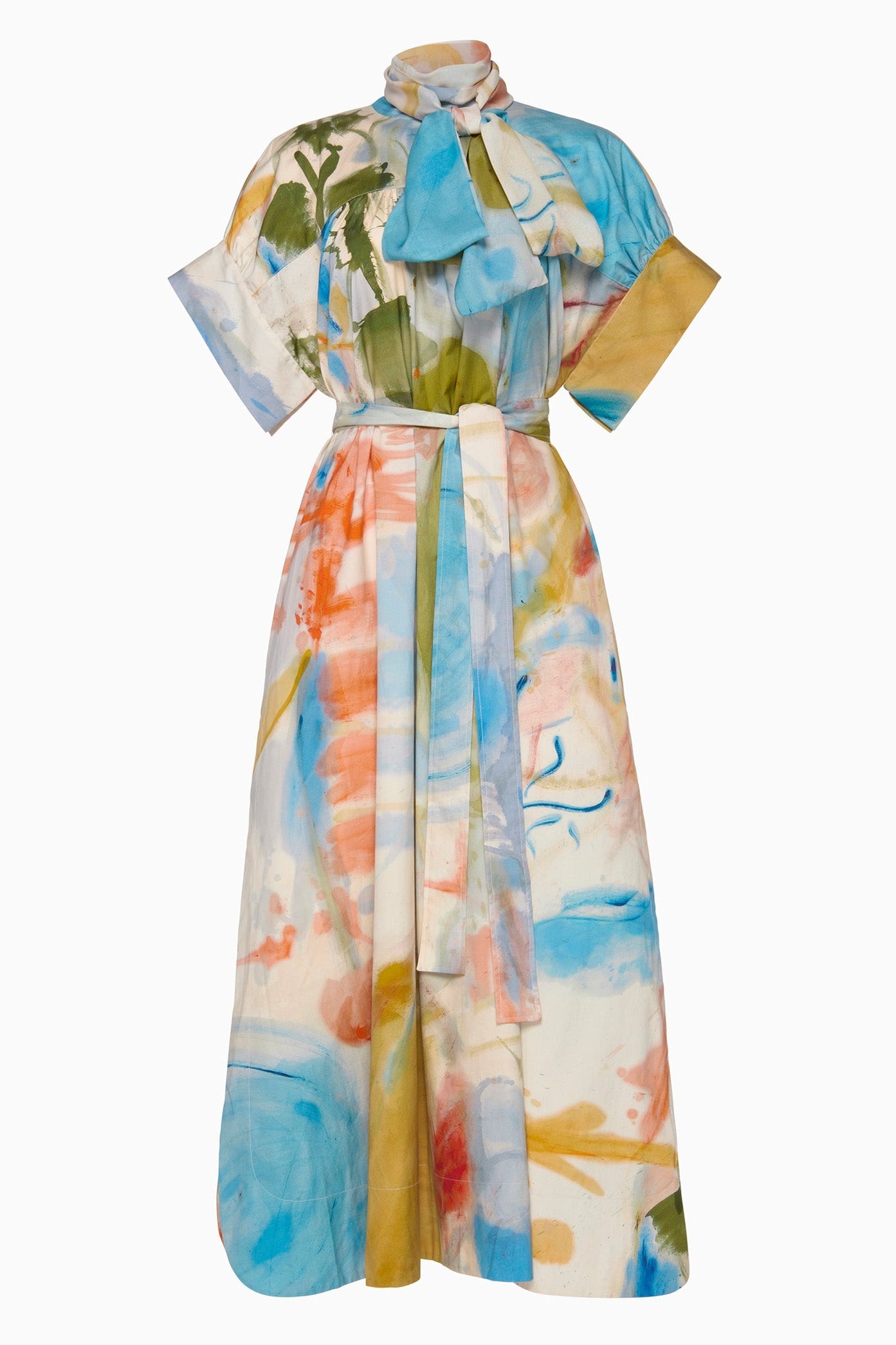The Studio Dress by Ulla Johnson is a midi-length design with colorful abstract print, short sleeves, a high neck with bow detail, and a matching fabric belt.