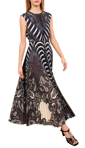 Woman wearing the Violeta Pleated Midi Dress by Ulla Johnson, a sleeveless midi dress featuring feather paisley patterns in dark and light tones, paired with black strappy heels.