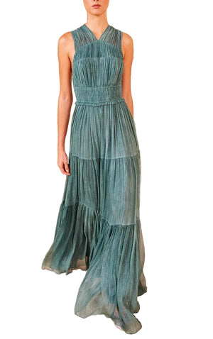 A person wearing the Ulla Johnson Freesia Gown, a sleeveless, floor-length dress in teal crinkle chiffon with a fitted waist, flowing silhouette, and pleated skirt.