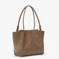 A taupe leather Victoria Beckham Victoria Tote with dual handles, minimal stitching, a structured shape, Italian craftsmanship, and suede lining is displayed on a plain white background.