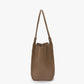 The Victoria Beckham Victoria Tote in taupe leather, featuring two handles and a suede lining, Italian crafted, is shown standing upright against a plain white background.