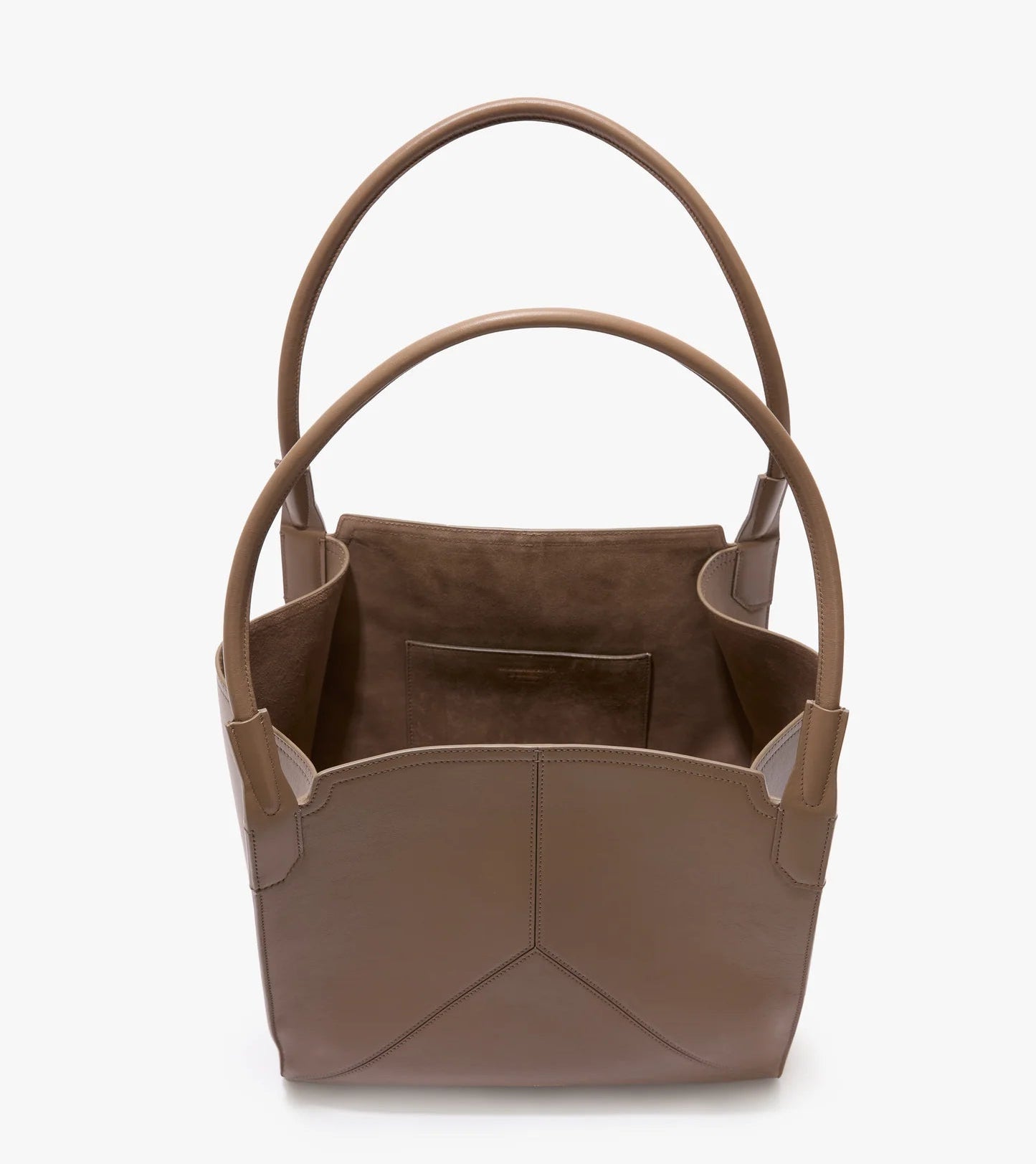 The Victoria Tote by Victoria Beckham is a taupe Italian leather tote with two handles, an open top, suede-lined interior, and a small inner pocket.