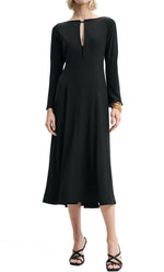 Person wearing a long-sleeved, black midi-length Dorothee Schumacher Sophisticated Volumes Dress with a front keyhole cutout, black strappy sandals, and a gold bracelet on the left wrist.