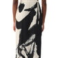 A person in a Pleated Sleeveless Shirtdress by Jason Wu Collection, featuring abstract black patterns, embodies effortless style. Viewed from the back, it showcases a unique shirtdress silhouette while they wear black heels.