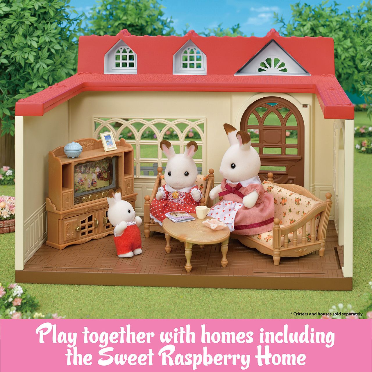 Three rabbit figurines relax in a cozy living room furnished with the Calico Critters Comfy Living Room Set inside a toy house featuring a red roof, wooden furniture, and a TV. Text at the bottom reads: “Play together with homes including the Sweet Raspberry Home.”.