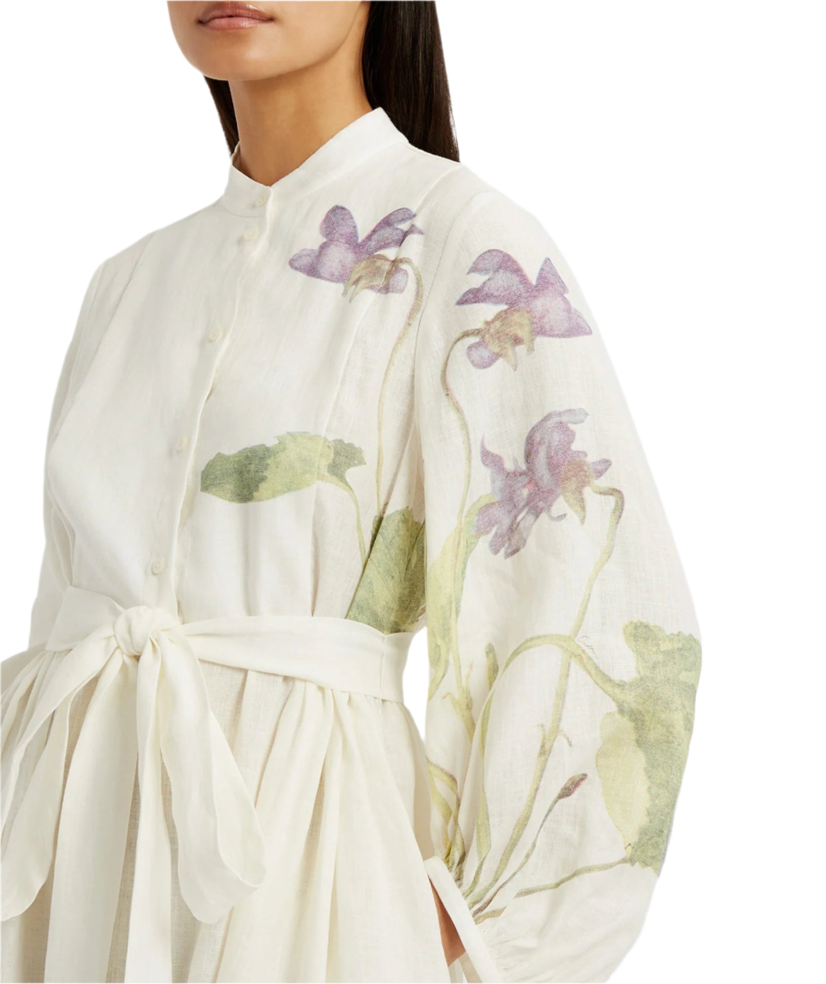 A woman wears the Erdem Long Sleeve Midi Dress With Tie Waist Detail, featuring a white linen design with sheer sleeves and purple and green botanical illustrations.