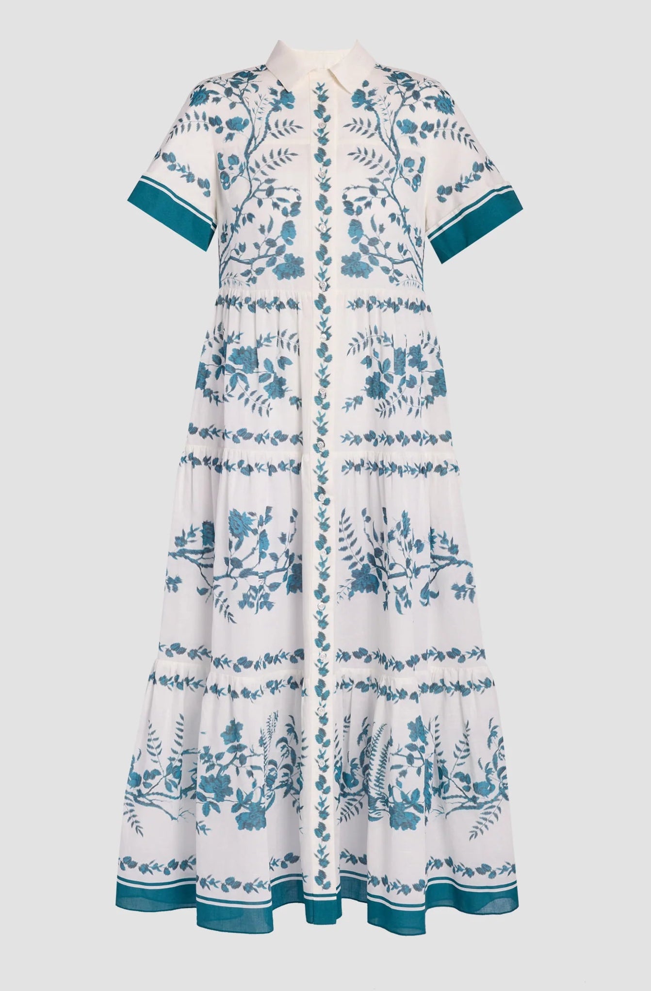 The Erdem Wild Fern Botanical Shirt Dress is a white midi cotton-linen blend with teal fern embroidery, tiered skirt, and teal-trimmed sleeves and hem, shown against a plain light backdrop.
