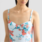 A woman wears the Erdem Trailing Poppy One Piece, a light blue floral swimsuit with moulded cups, thin straps, and a sweetheart neckline, shown from shoulders to mid-torso.